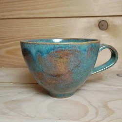 Entonnoir en grès bleu / vert posé sur une table.