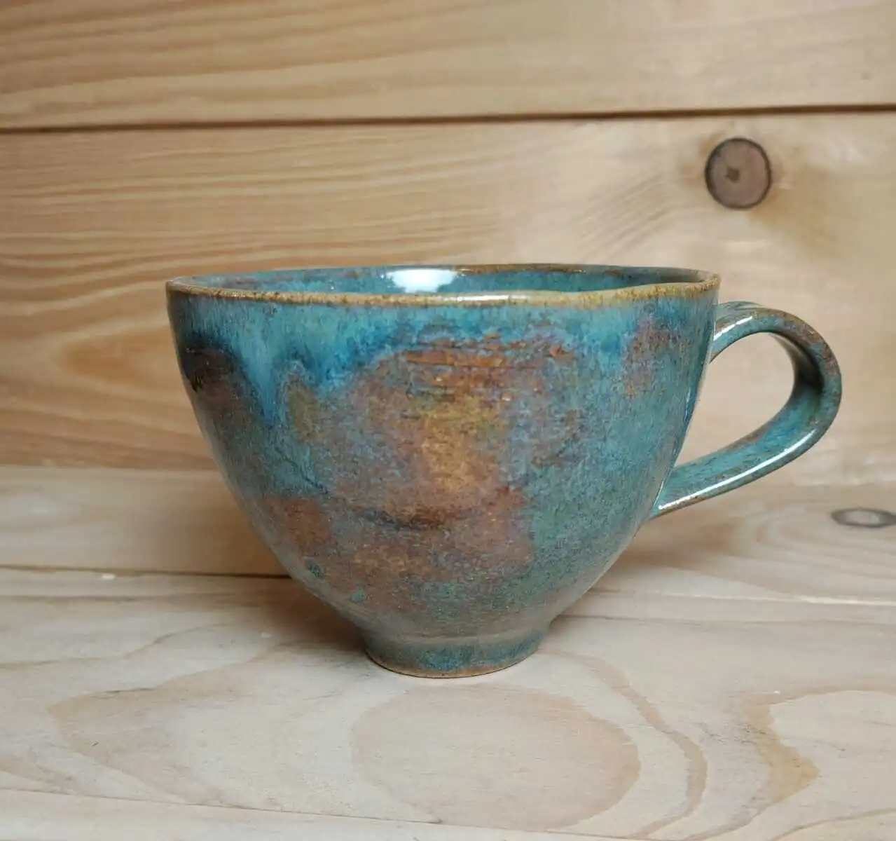 Entonnoir en grès bleu / vert posé sur une table.